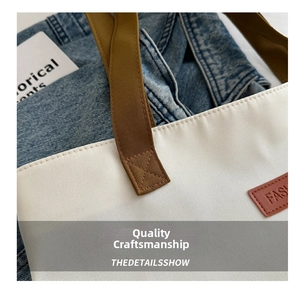 Detailed close-up of canvas tote bag stitching with brown leather strap and reinforced seams