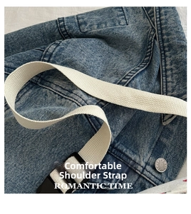 Detail of blue denim bag with white canvas strap and adjustable buckle connector