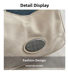 Detail of cream shoulder bag showing crinkled texture and silver oval logo plaque