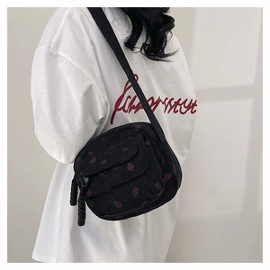 Detail of strawberry pattern on black corduroy crossbody bag with adjustable shoulder strap