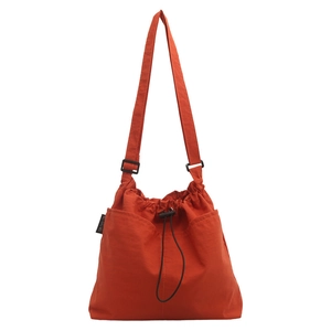 Large orange nylon drawstring tote bag with adjustable shoulder strap and side pockets
