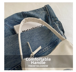 Detail of white matte leather handbag with slim handle and casual denim background