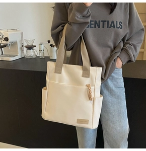 Dettaglio della borsa in tela con etichetta in pelle e ciondolo zip in corda marrone