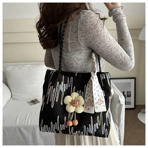 Detail of black quilted canvas tote with colorful embroidery and yellow floral charm
