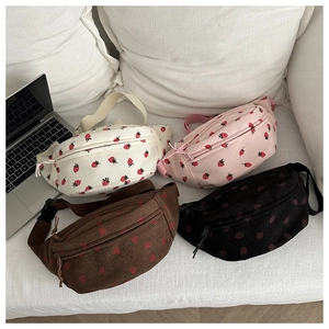 Corduroy saddle bags with strawberry prints in four colors on a white sofa backdrop
