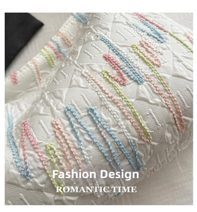 Detail of white tote bag with quilted diamond pattern and colorful wave embroidery