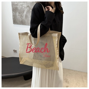 Dettaglio della borsa tote in rete beige con scritta Beach Vibes rosa e manici robusti