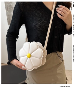 Detail of white daisy floral shoulder bag with yellow center on model outfit