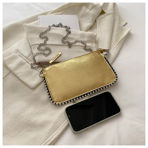 Detailed view of gold textured crossbody bag with silver bead trim and metal chain strap