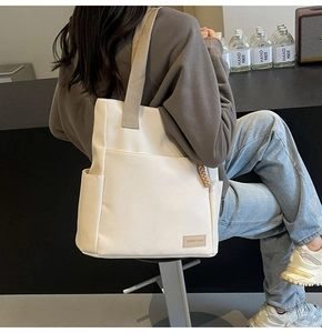 Vista dettagliata di una grande borsa tote bianca con tasche laterali e dettagli in corda