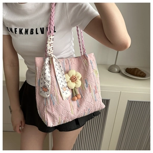 Detail of pink quilted tote bag with floral charm, woven handle, and printed silk scarf
