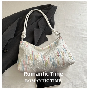 Detailed view of white quilted shoulder bag with vibrant colorful vertical embroidery