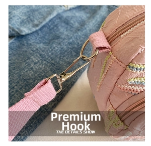 Macro view of silver metal hooks and pink textured fabric on a stylish crossbody bag