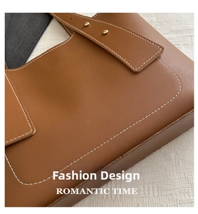 Close-up of caramel leather tote featuring contrast white stitching and gold metal rivets
