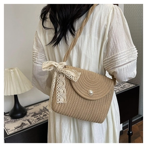 Detail of woven crossbody bag with pearl button closure and beige lace ribbon bow