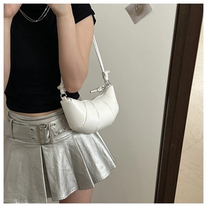 Detail of white leather croissant bag featuring segment stitching and knotted shoulder strap