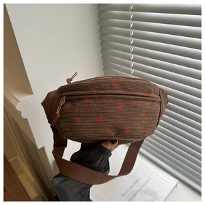 Detail of corduroy bag featuring embroidered strawberry patterns and woven strap texture