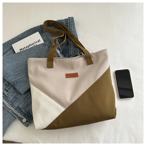 Détail du sac cabas en toile avec coutures géométriques et étiquette en cuir marron