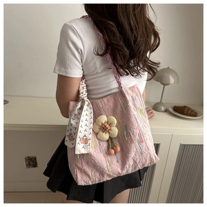 Pink tote bag detail with textured fabric, sunflower pendant, and silk scarf handle accent