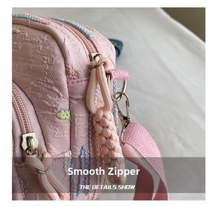 Detail of pink crossbody bag showing the textured fabric and smooth metal zipper