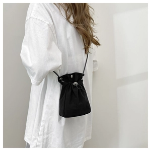 Minimalist black drawstring bucket bag shown with metal hardware and thin crossbody strap