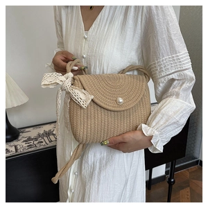 Detail of woven straw crossbody bag with white lace bow and imitation pearl buckle