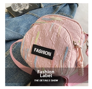 Close-up of pink crossbody bag with embossed patterns and colorful knitted stripes