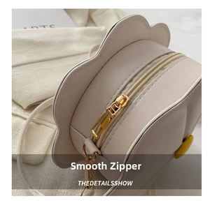 Detailed macro of smooth metal zipper and leather texture on flower-shaped crossbody bag