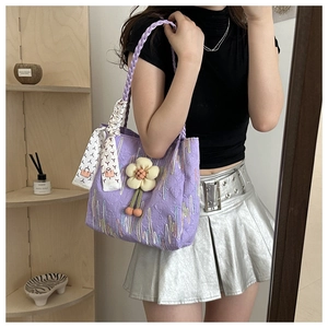 Detail of purple quilted canvas tote bag with woven handles and white floral charms