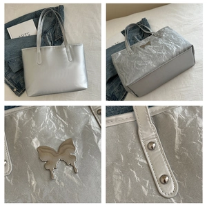 Detail of silver metallic tote bag featuring pleated texture and butterfly buckle