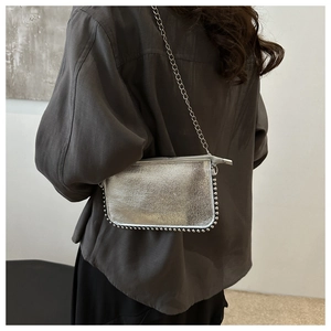 Detail of silver metallic handbag with chain strap and studded edges on shoulder