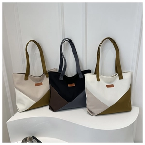 Three minimalist color-block canvas tote bags with leather labels on white podiums