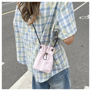 Detail view of pink nylon bucket bag with drawstring closure and slim black strap