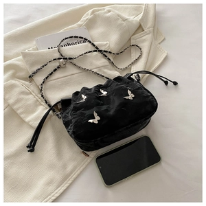 Detail of black drawstring bucket bag with silver butterfly charms and chain strap