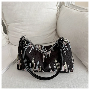 Close-up of black tote bag with colorful zigzag embroidery and knotted leather handle