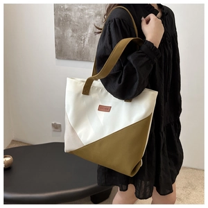 Detail of color-block geometric tote bag featuring a leather FASHION label and green strap