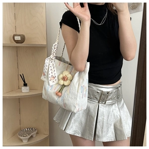 Close-up of white canvas tote bag with silk scarf handle and 3D floral charm detail