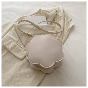 Detailed top view of a cream-colored flower shaped crossbody bag on a beige blazer