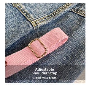 Detail of pink woven adjustable strap with rectangular metal buckle on denim fabric