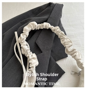 Close-up of cream pleated scrunchie shoulder strap and silver zipper on crescent bag