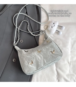 Close-up of silver tote bag with metallic butterfly accents and a white plush charm