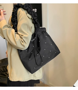 Detail of black tote bag with silver metal rivets and ruffled handle decoration