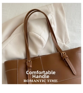 Gros plan d'un sac cabas en cuir marron avec surpiqûres blanches et boucle dorée