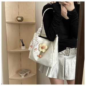 Close-up of white nylon tote with 3D flower charm, cherry charms, and silk scarf detail