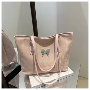 Macro shot of pink tote bag showing pleated leather texture and silver butterfly ornament