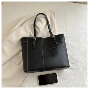 Détail du sac cabas en cuir noir avec surpiqûres blanches et boucles métalliques réglables