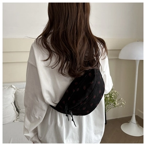 Model wearing black floral corduroy chest bag with adjustable strap in minimalist room