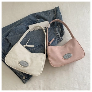 Detail of white and pink pleated crescent underarm bags on denim jacket backdrop