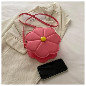 Detailansicht einer rosa blumenförmigen Umhängetasche mit Blütenblatt auf Beige-Sakko