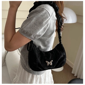 Detail of black crescent shoulder bag with metallic butterfly and scrunchie strap